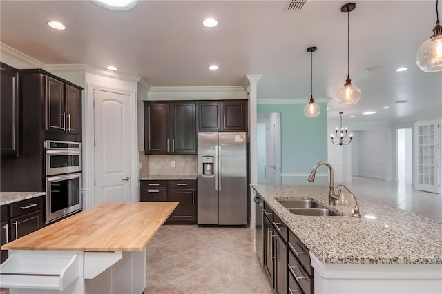 kitchen featuring a center island with sink, visible vents, stainless steel appliances, dark brown cabinets, and a sink