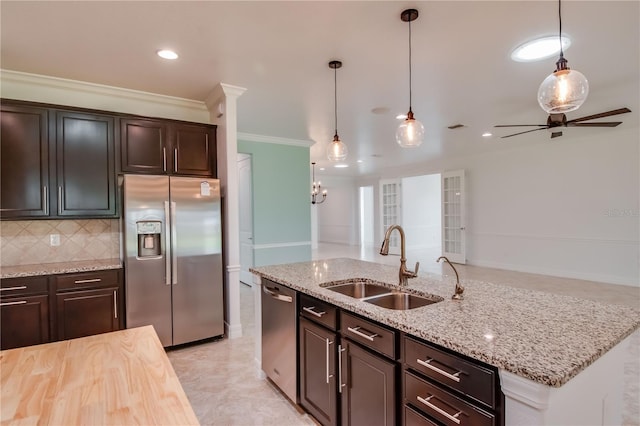 kitchen featuring a kitchen island with sink, a sink, appliances with stainless steel finishes, tasteful backsplash, and pendant lighting