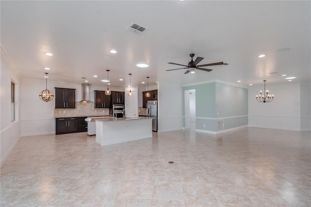 kitchen with open floor plan, wall chimney exhaust hood, appliances with stainless steel finishes, and visible vents