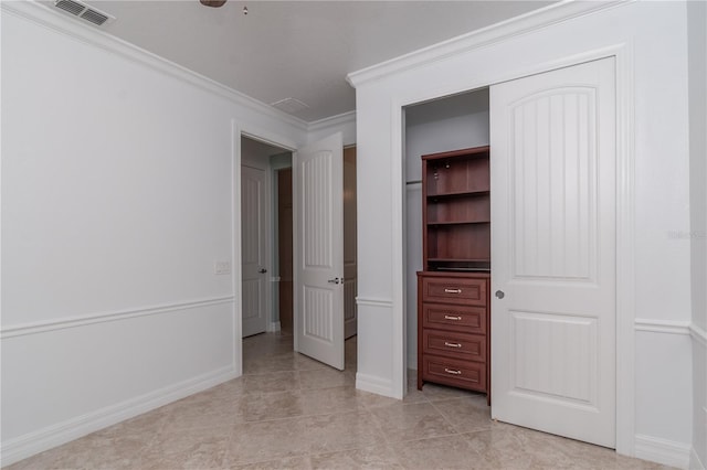 unfurnished bedroom with crown molding, light tile patterned floors, a closet, visible vents, and baseboards