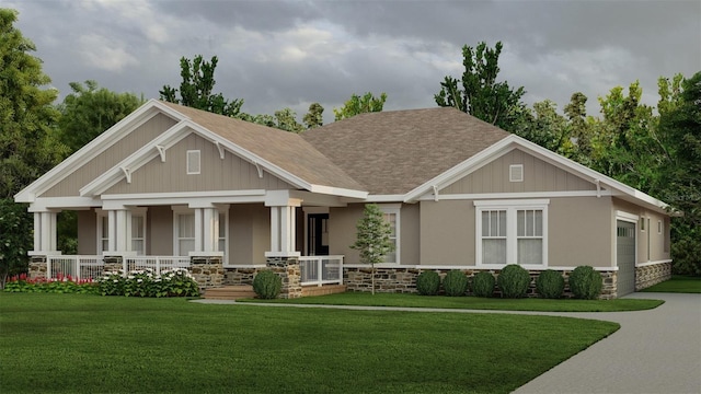 craftsman inspired home featuring covered porch, stone siding, a front lawn, and roof with shingles