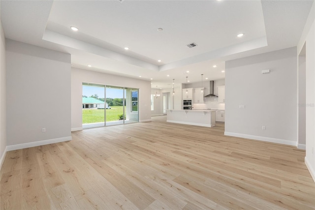 1929 NW 85th Loop, Ocala, FL 34475 - unfurnished living room featuring a tray ceiling, light wood-type flooring, and recessed lighting