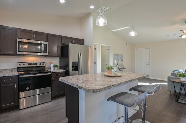 kitchen with a kitchen island, appliances with stainless steel finishes, a breakfast bar, and decorative light fixtures