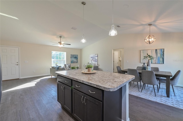 kitchen featuring dark wood-style floors, a center island, light countertops, hanging light fixtures, and open floor plan