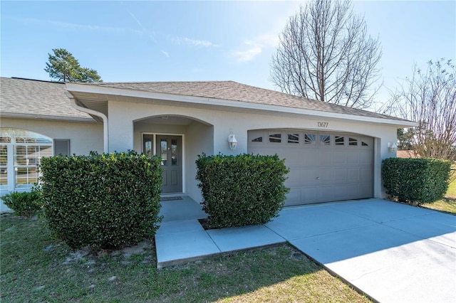 single story home with a garage, roof with shingles, driveway, and stucco siding