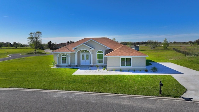 mediterranean / spanish house with stucco siding, driveway, and a front yard