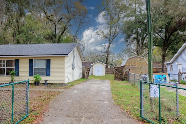 view of home's exterior with a shed, a gate, fence, and an outbuilding