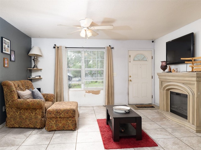 living area with a ceiling fan, a glass covered fireplace, and light tile patterned floors