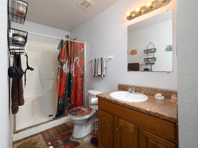 bathroom with toilet, a shower stall, visible vents, and vanity