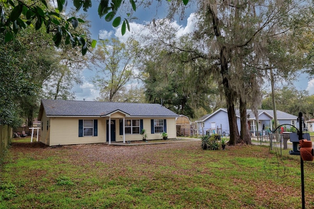 ranch-style house featuring fence and a front lawn