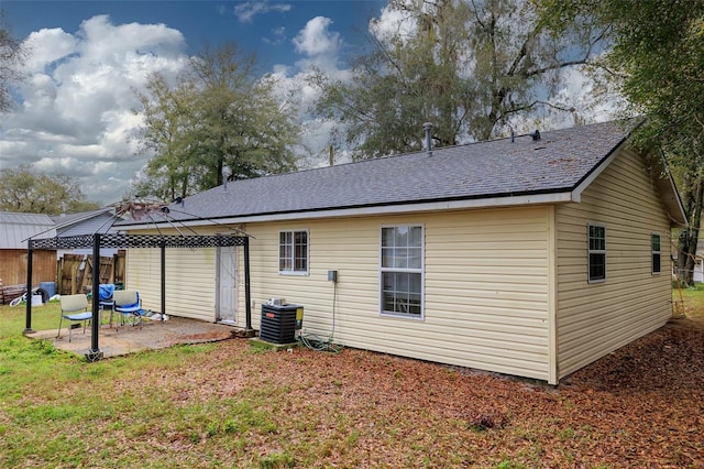 back of house with roof with shingles, a gazebo, a yard, a patio area, and central AC