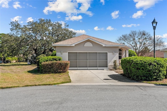 view of front facade with concrete driveway, a front lawn, an attached garage, and stucco siding