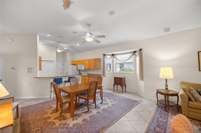 dining space featuring light tile patterned floors, ceiling fan, vaulted ceiling, and baseboards