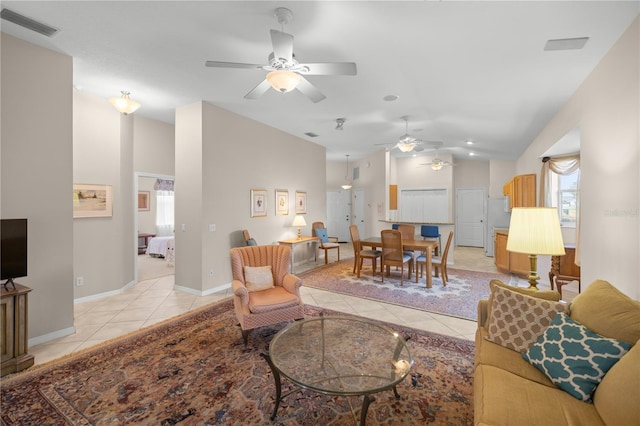 living room with light tile patterned flooring, vaulted ceiling, visible vents, and baseboards