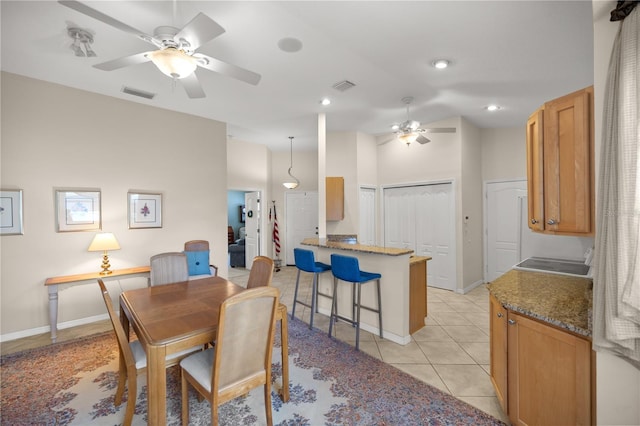 dining space featuring light tile patterned floors, visible vents, vaulted ceiling, and a ceiling fan