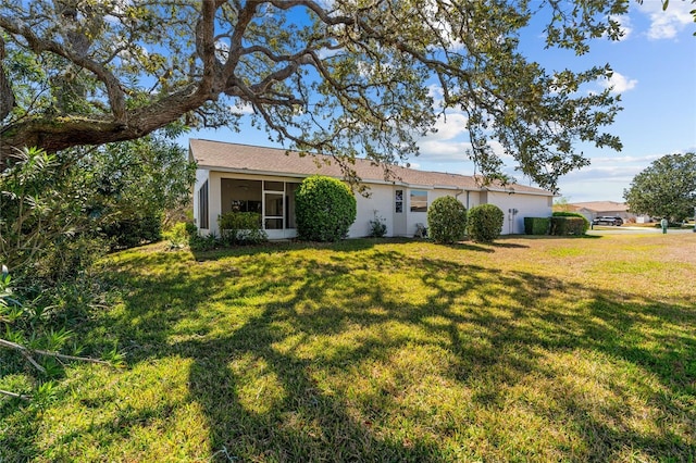 single story home with a front yard, a sunroom, and stucco siding