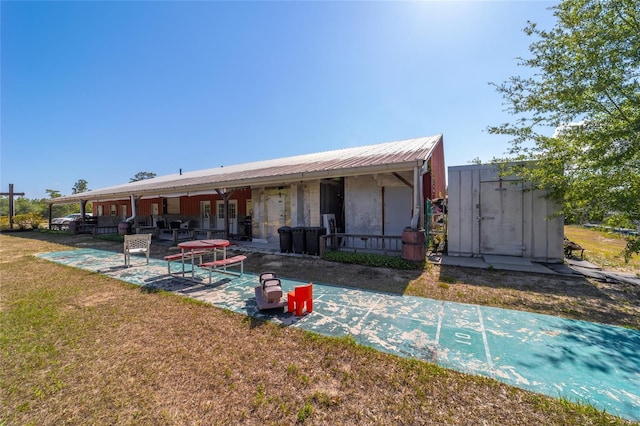 back of property featuring a yard and metal roof