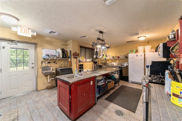 kitchen with stainless steel appliances, hanging light fixtures, a sink, and visible vents