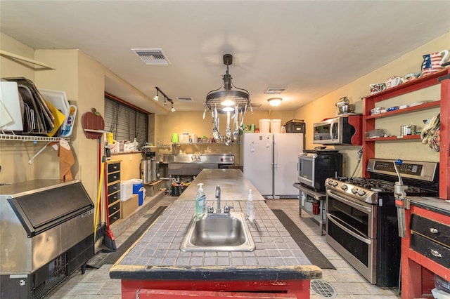 kitchen with visible vents, tile counters, appliances with stainless steel finishes, open shelves, and a sink