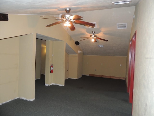 interior space with visible vents, vaulted ceiling, and dark colored carpet