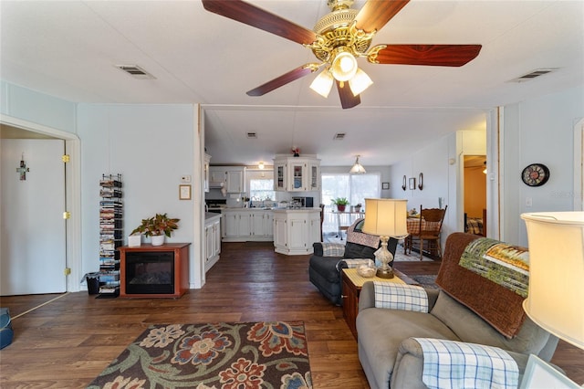 living room with a ceiling fan, dark wood-style flooring, and visible vents