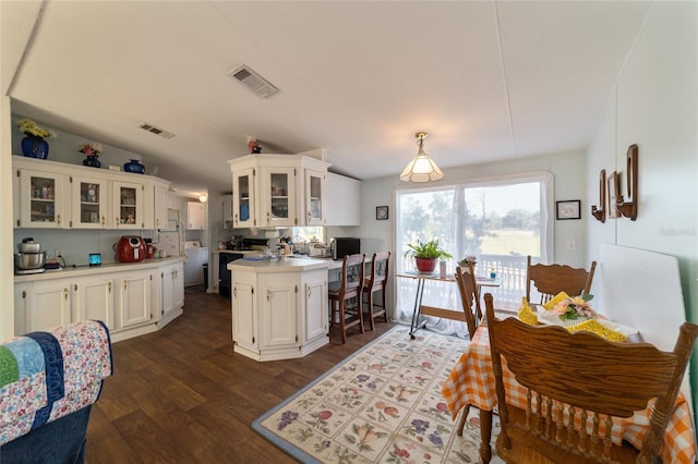 kitchen featuring visible vents, light countertops, glass insert cabinets, and a center island