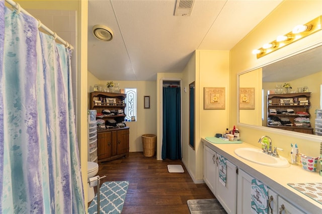 bathroom with visible vents, a shower with shower curtain, toilet, wood finished floors, and vanity