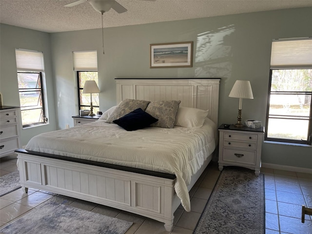 bedroom with a textured ceiling, ceiling fan, multiple windows, and baseboards