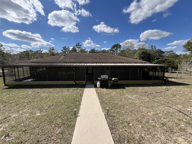 back of property with a yard and a sunroom