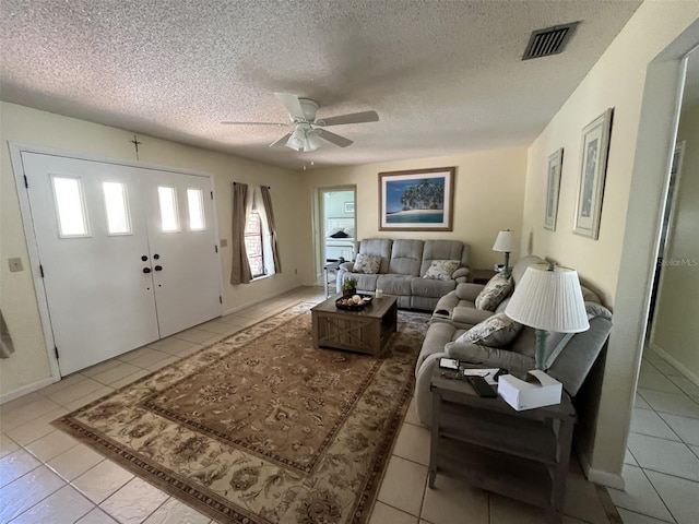 living room with a textured ceiling, light tile patterned flooring, and visible vents