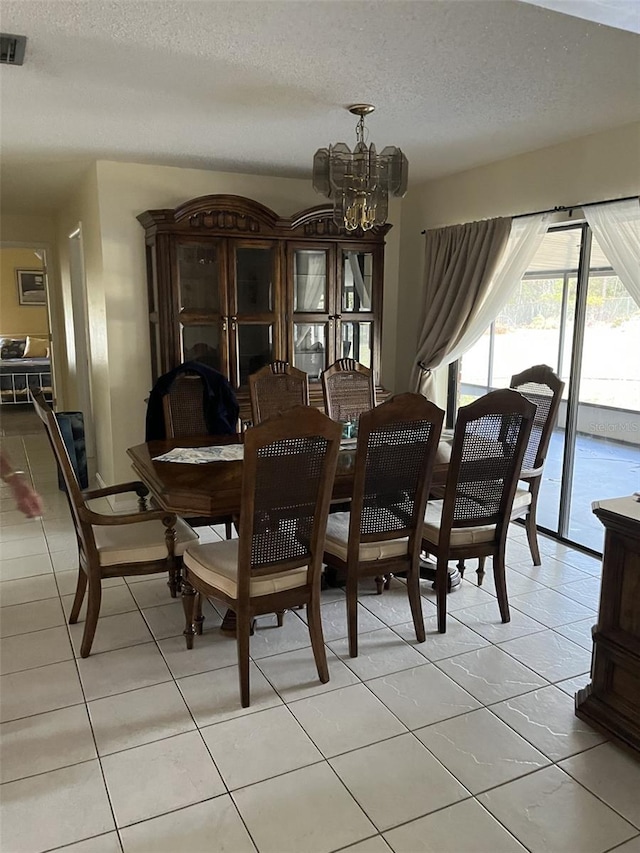 dining room with light tile patterned flooring, a notable chandelier, and a textured ceiling