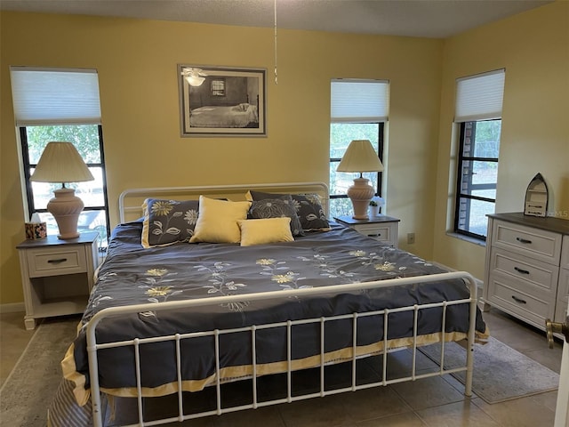 bedroom featuring baseboards, multiple windows, and tile patterned floors