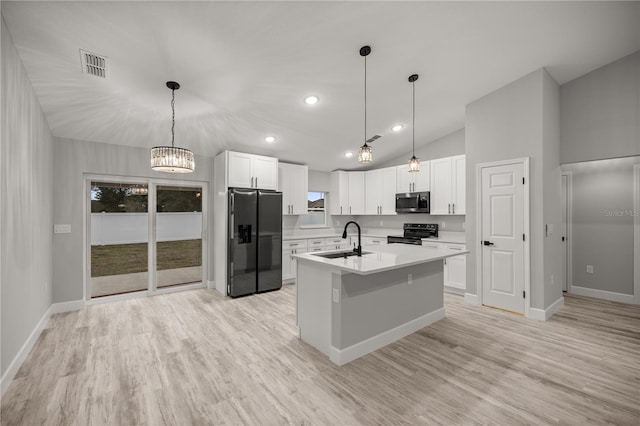 kitchen with range with electric cooktop, stainless steel microwave, light countertops, white cabinetry, and black fridge