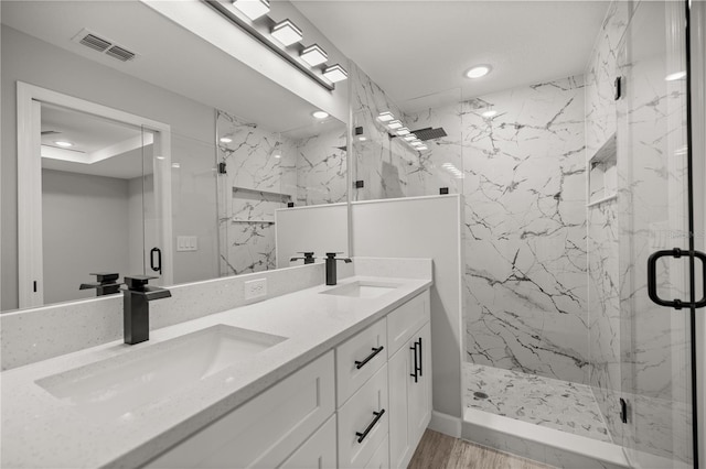 full bathroom with a marble finish shower, wood finished floors, a sink, and visible vents