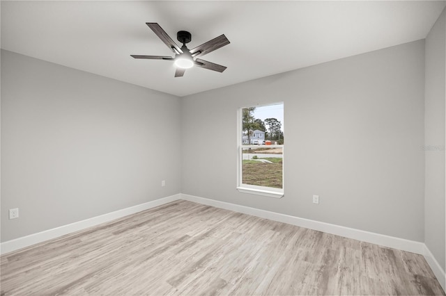 spare room with a ceiling fan, light wood-type flooring, and baseboards