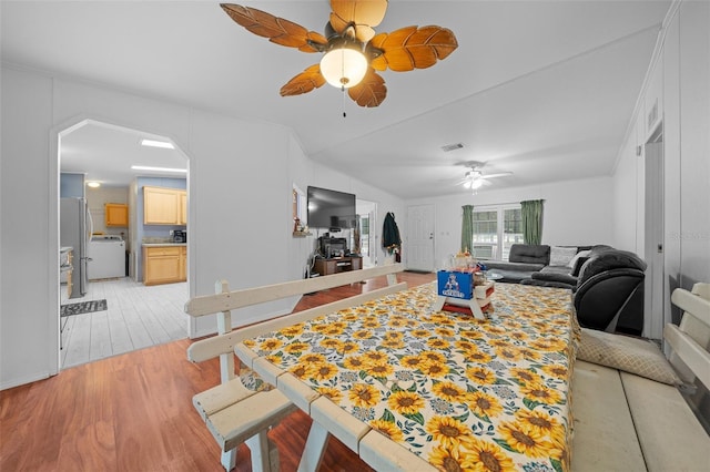 living area featuring washer / dryer, visible vents, arched walkways, ceiling fan, and light wood-type flooring