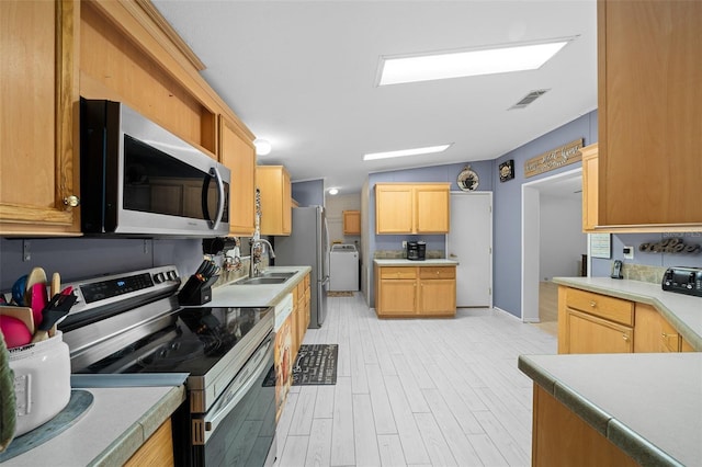 kitchen featuring stainless steel appliances, light countertops, visible vents, a sink, and washer / dryer