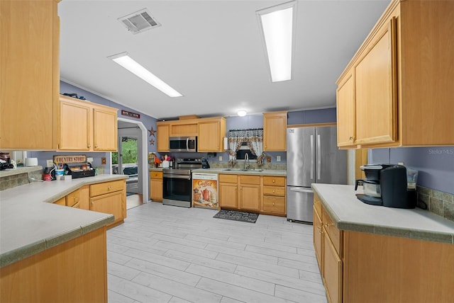 kitchen featuring light countertops, visible vents, appliances with stainless steel finishes, light brown cabinets, and a sink