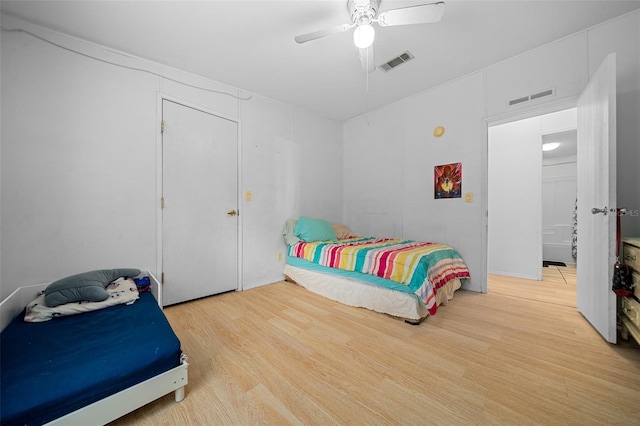 bedroom featuring a ceiling fan, visible vents, and wood finished floors