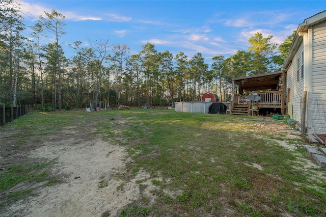 view of yard featuring a deck, fence, and a pool