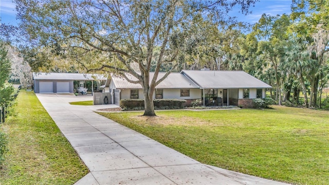 ranch-style house with a garage, metal roof, a front yard, and an outdoor structure