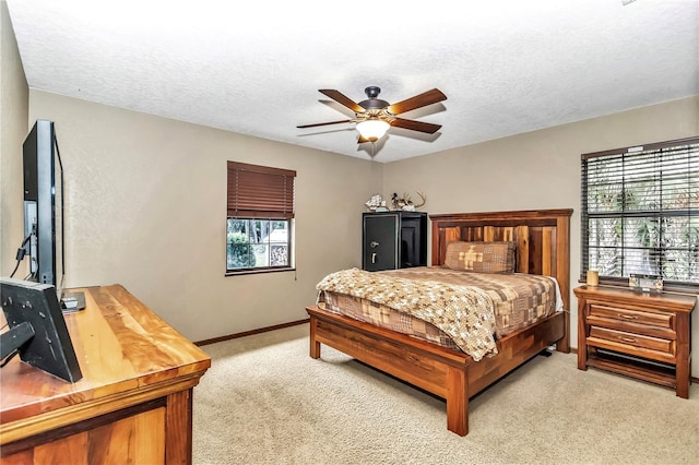 bedroom featuring a textured ceiling, baseboards, a ceiling fan, and light colored carpet