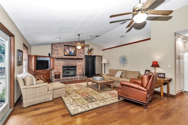 living room with a textured ceiling, a fireplace, vaulted ceiling, and wood finished floors