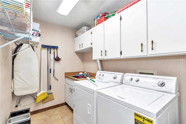 clothes washing area featuring light tile patterned floors, separate washer and dryer, a sink, and cabinet space