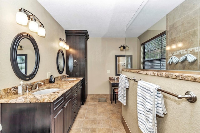 bathroom featuring double vanity, tile patterned flooring, a textured ceiling, and a sink