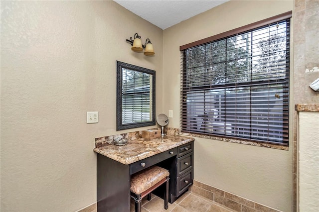 bathroom featuring a textured wall, vanity, and baseboards