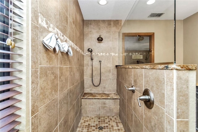 bathroom with recessed lighting, visible vents, and a tile shower