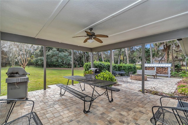 view of patio with ceiling fan, fence, a fire pit, and grilling area