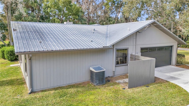 view of property exterior with metal roof, central AC, driveway, and a lawn