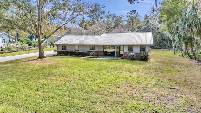 ranch-style house featuring fence, metal roof, and a front yard